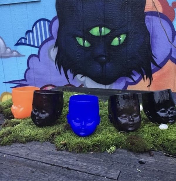 Set of Baby Head Cups in fron of a cat mural