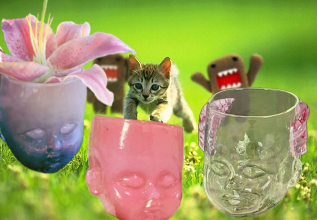 A kitten is pursued by two plushy monsters Green Meadow. Into a foreground featuring a purple, pink, and cherub Baby Head Cup.