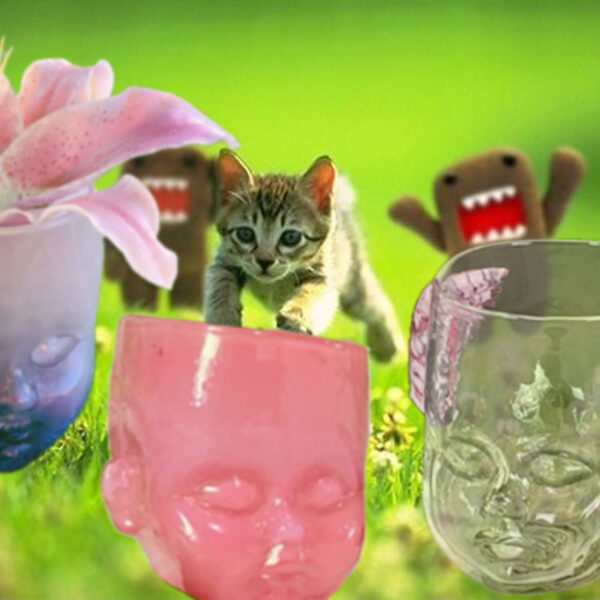 A kitten is pursued by two plushy monsters Green Meadow. Into a foreground featuring a purple, pink, and cherub Baby Head Cup.